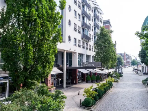 Das Madison Hotel Hamburg mit Außenbereich und Blick auf eine kopfsteingepflasterte Straße.