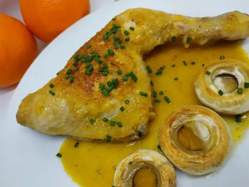 Pollo a la naranja jugoso con salsa cítrica, acompañado de champiñones y cebollino fresco.