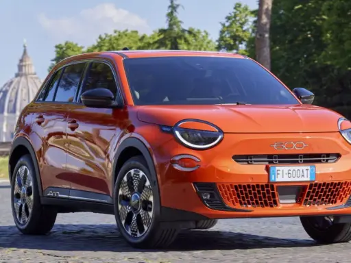 El nuevo Fiat 600, un SUV naranja vibrante, se exhibe con elegancia frente a la cúpula de San Pedro en Roma.