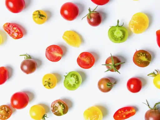 Un assortiment coloré de meilleures tomates cocktail, entières et coupées, sur fond blanc.