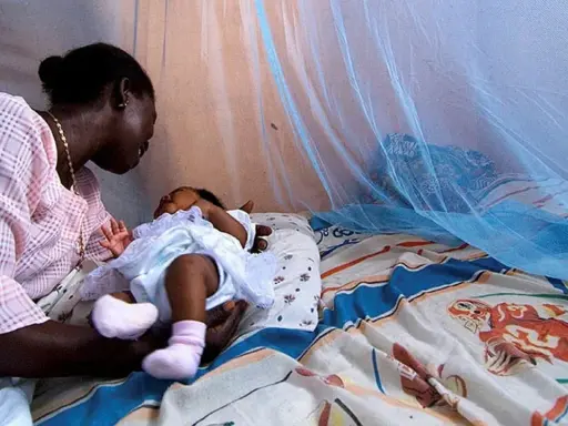 Mor och barn under myggnät, skyddade från malaria. Bali är en plats där kampen mot malaria fortsätter.
