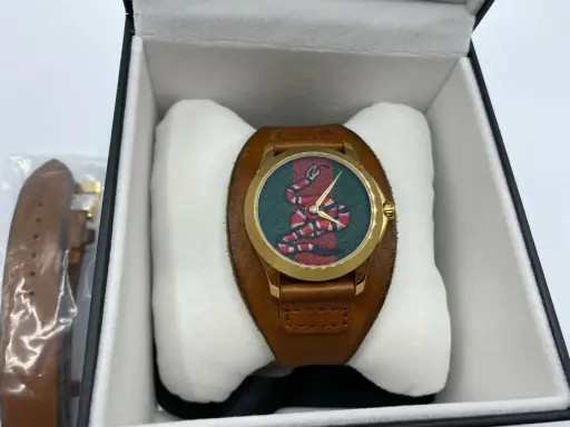 Orologio Gucci serpente con quadrante verde e cinturino in pelle marrone, presentato nella sua scatola.