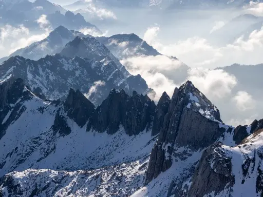 Majestatyczne Tatry Wysokie, ośnieżone szczyty i mgliste doliny tworzą zapierający dech w piersiach krajobraz.