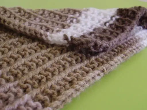 Bufanda tejida con patrones puntos reversibles a dos agujas, en tonos marrones y blanco.