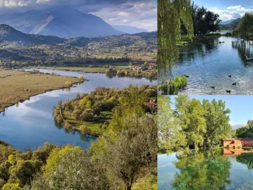Paesaggio incantevole del lago di Posta Fibreno, con montagne sullo sfondo, un fiume serpeggiante e un antico mulino rosso riflesso nelle acque cristalline.