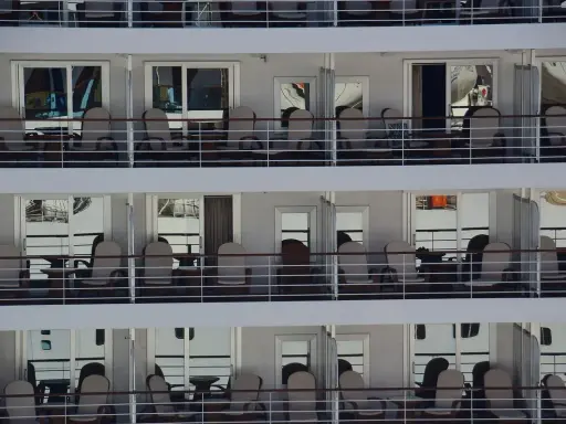 File di cabine crociera con balconi arredati con sedie e tavolini, pronte per accogliere i passeggeri.