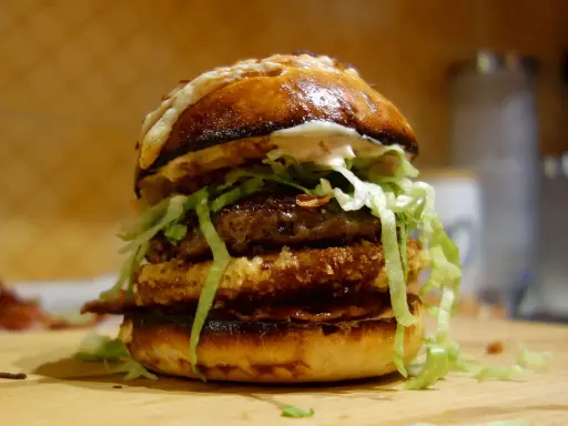 Apetyczny burger drwala przepis: podwójna wołowina, chrupiący panierowany kotlet, sałata i sos na puszczy.