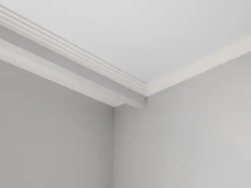 Angolo di una stanza con pareti grigie e soffitto bianco. Si nota uno stacco tra parete e soffitto con una modanatura decorativa.