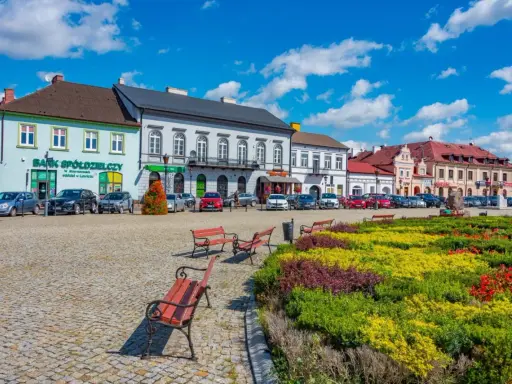 Kolorowy rynek z kwitnącymi rabatami i ławkami, idealne miejsce na wyjazd na weekend.