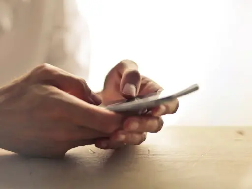 Dłonie trzymające telefon, jakby zastanawiając się, czy na odwyku można mieć telefon.