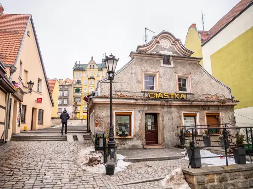 Kłodzko rynek. Kamienne uliczki i kolorowe kamienice tworzą urokliwy klimat. Na pierwszym planie budynek z napisem "Ciastka".