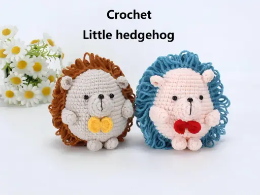 Dos adorables erizos de crochet, uno beige con pajarita amarilla y otro rosa con pajarita roja, posan junto a un ramo de margaritas.