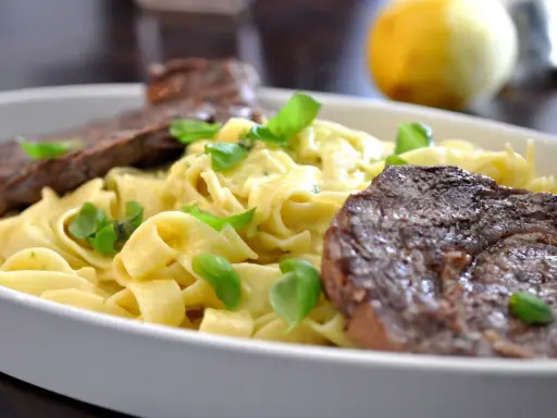 En krämig pastarätt med tagliatelle, garnerad med färsk basilika och serverad med saftig entrecote.