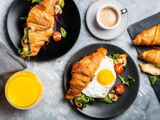 Typowe amerykańskie śniadanie: croissant z jajkiem sadzonym, pomidorkami i grzybami, do tego kawa i sok.