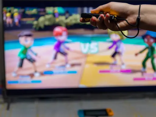 Ręka trzymająca kontroler do gry, na ekranie telewizora widać kolorowe postacie z gry ruchowej Nintendo Switch.