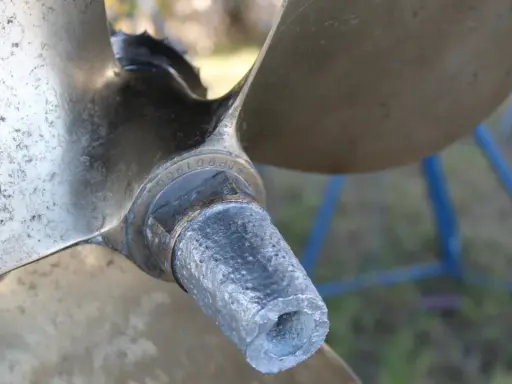 Gros plan sur l'hélice d'un bateau, montrant l'usure de l'anode et les détails gravés.