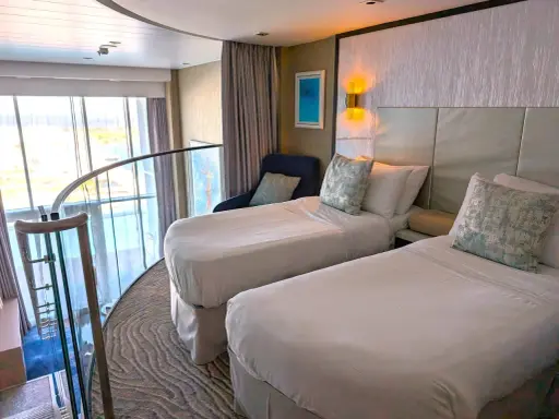 Ecco cosa trovo in cabina MSC: due letti singoli, una poltrona blu, quadri astratti e una grande finestra con vista panoramica.