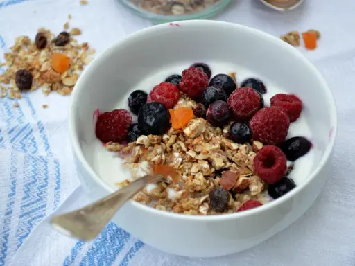 En skål med yoghurt, fil och flingor toppad med färska hallon, blåbär och torkad frukt. En perfekt start på dagen!