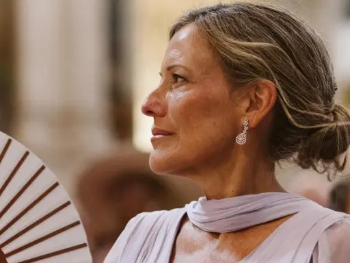 Elegantes peinados para madrinas de 60 años: un recogido bajo y pulido, con pendientes de brillantes, ideal para un evento especial.