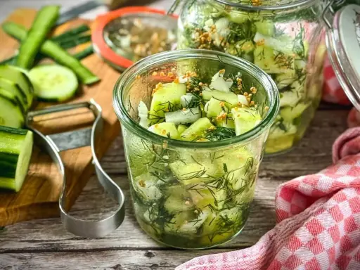 Schnellgurken rezept ohne kochen: Frische Gurkenscheiben mit Dill und Senfkörnern in Gläsern, bereit zum Einlegen.