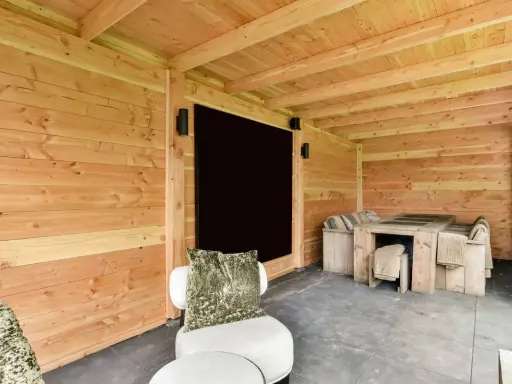 Un'accogliente dependance in legno con tavolo e sedute, perfetta per idee di relax all'aperto.
