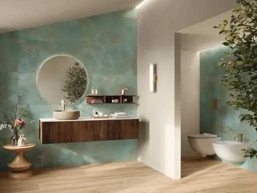 Elegante bagno verde petrolio e legno con lavabo in pietra, specchio rotondo e bidet sospeso.