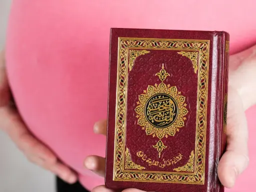 Schwanger, hält eine Frau den Koran. Im Islam gibt es Erleichterungen beim Fasten während der Schwangerschaft.