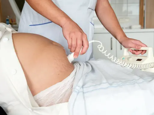 En barnmorska utför en ultraljudsundersökning på en gravid mage, en del av specialistmödravård.