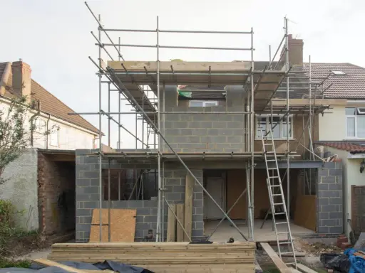 Construction d'une maison : échafaudages, blocs de béton, poutres métalliques. Penser à tout quand on fait construire sa maison.