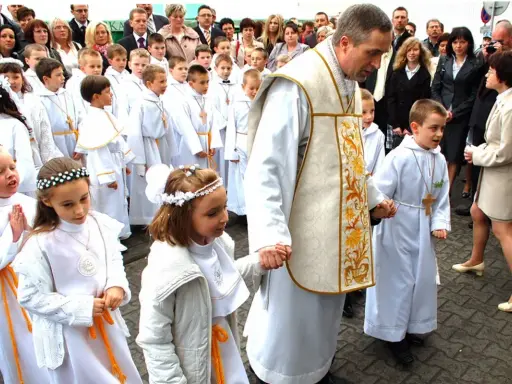 Dzieci w białych strojach, kiedy jest komunia, idą z księdzem.