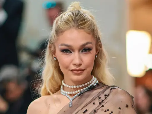 Gigi Hadid luce un maquillaje con perlas, con pequeños adornos brillantes en los ojos y un collar de perlas.