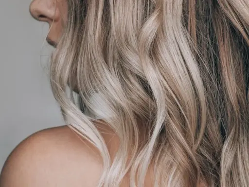 Piękne, falowane włosy w odcieniu blond, uzyskane bez użycia rozjaśniacza. Naturalny efekt i subtelne refleksy.