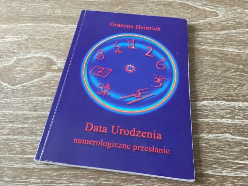 Okładka książki "Data Urodzenia numerologiczne przesłanie" Grażyny Heinrich. Centralny element to okrąg z cyframi i symbolami, sugerujący analizę liczby numerologicznej.