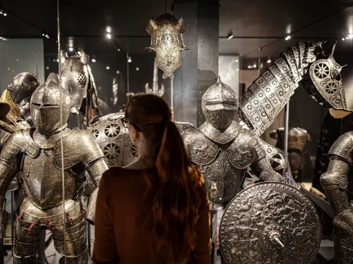 En kvinna betraktar rustningar och en hästrustning på Livrustkammaren Stockholm.