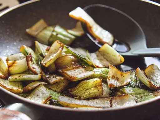 Gebratener Mangold und Pak Choi in einer Pfanne, leicht karamellisiert und mit einem Löffel serviert.
