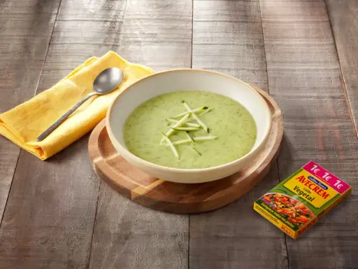Crema de calabacín para niños, servida en un cuenco blanco sobre tabla de madera. Al lado, un paquete de caldo vegetal Avecrem.