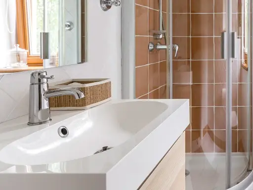 Bagno moderno con lavabo bianco, rubinetteria cromata e doccia con piastrelle color terra. Ideale per misure minime mini bagni piccoli progetti.