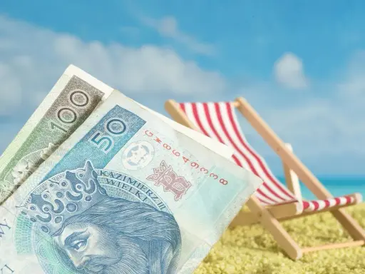 Pieniądze na plaży, leżak i błękitne niebo. Czy to symboliczne przedstawienie opłaty klimatycznej za wakacyjny wypoczynek?