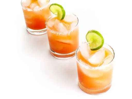 Drei erfrischende Salty Dog Cocktails mit Eis und Limettenspalten, bereit zum Genießen.