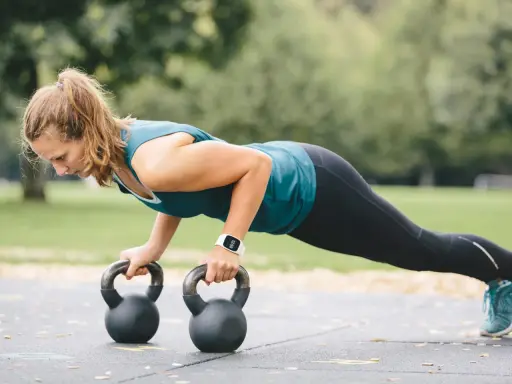 Frau macht Liegestütze mit Kettlebells. Ein effektiver Kettlebell Trainingsplan für zu Hause.