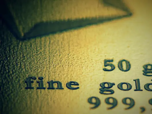 Zbliżenie na tekst "fine gold 50 g 999,9" wybity na powierzchni złota.