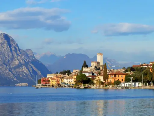 Borgo sul lago di Garda con castello e montagne sullo sfondo. Un luogo incantevole da esplorare, scopri cosa vedere!