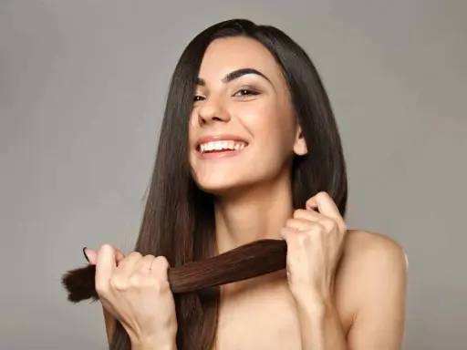 Mujer sonriente muestra su cabello largo y sedoso, un ejemplo de cómo cuidar el pelo para que luzca saludable y brillante.
