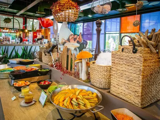 Buffet coloré avec des plats de courges, salades et fruits. Décoration ludique avec des champignons et un personnage de conte de fées, dans l'ambiance du resto Futuroscope.