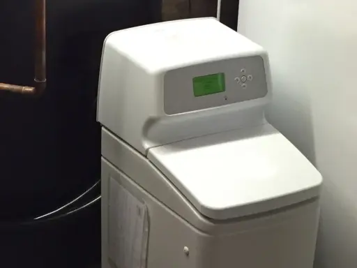 Adoucisseur d'eau blanc avec écran vert, un avantage pour une eau plus douce et une maison protégée.