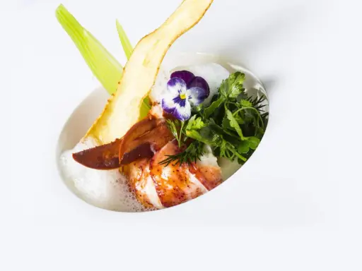 Homard poêlé, écume légère, chips de légume et fleur, une spécialité jurassienne raffinée.