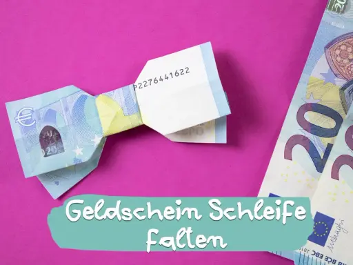Eine Fliege aus Geld falten ist eine kreative Idee für Geschenke. Hier siehst du eine gefaltete Geld-Fliege auf pinkem Hintergrund.