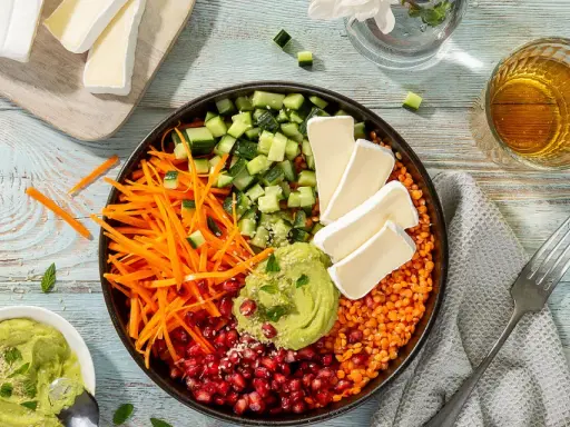 Bunter rote Linsen Salat mit Gurke, Karottenstreifen, Granatapfelkernen, Avocado-Dip und Brie-Käse.