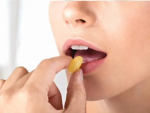 Donna inserisce una capsula gialla in bocca. Per l'assunzione di Ciproxin, stomaco pieno o vuoto, consultare il medico.