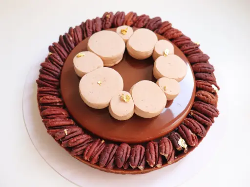 Tarte chocolat noix de pécan, un délice gourmand avec une ganache brillante et des touches de feuille d'or.